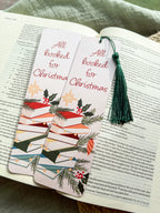 Christmas-themed pun "All Booked for Christmas" bookmarks on an open book with a textured surface in the background.