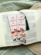 Christmas-themed pun "All Booked for Christmas" bookmarks on an open book with a textured surface in the background.