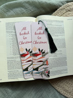 Christmas-themed pun "All Booked for Christmas" bookmarks on an open book with a textured surface in the background.