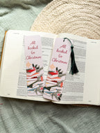 Christmas-themed pun "All Booked for Christmas" bookmarks on an open book with a textured surface in the background.