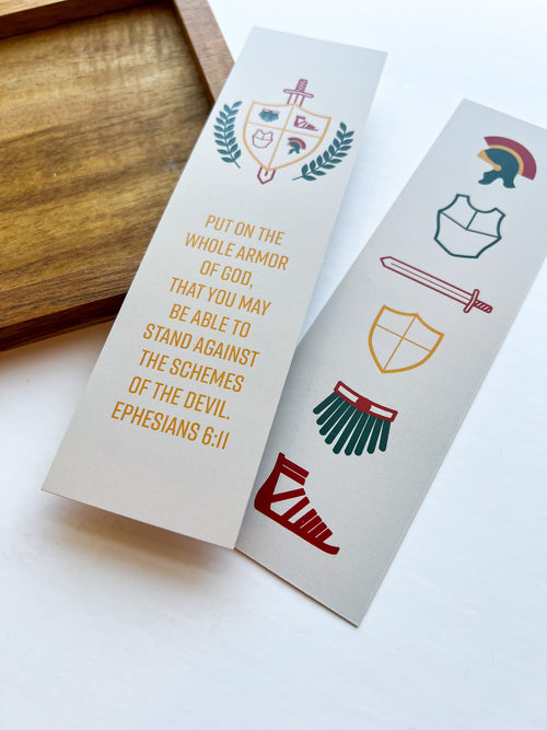 Two bookmarks with a religious theme, featuring a castle, shield, and sword design, with the verse 'Put on the whole armor of God, that you may stand against the schemes of the devil.' - Ephesians 6:11.