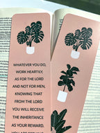 front and back rectangular bookmarks with rounded corners, featuring a green plant illustration and a Colossians 3:23-24 Bible verse, placed on a patterned fabric surface.