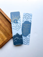 Two bookmarks with a mountain and cloud design in blue and orange colors, Psalm 25:4-5 bible verse written, placed on a white surface.