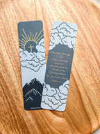Two bookmarks with a mountain and cloud design in blue and orange colors, Psalm 25:4-5 bible verse written, placed on a wooden surface.