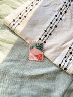 A magnet shaped like a postage stamp with an illustration of the Utah state, placed on a woven surface.