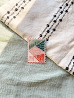 A magnet shaped like a postage stamp with an illustration of the Utah state, placed on a woven surface.