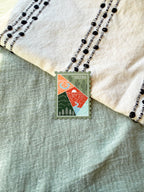 Colorful postage stamp design of Arizona held by a hand against a textured fabric background