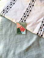 Colorful postage stamp design of Arizona held by a hand against a textured fabric background