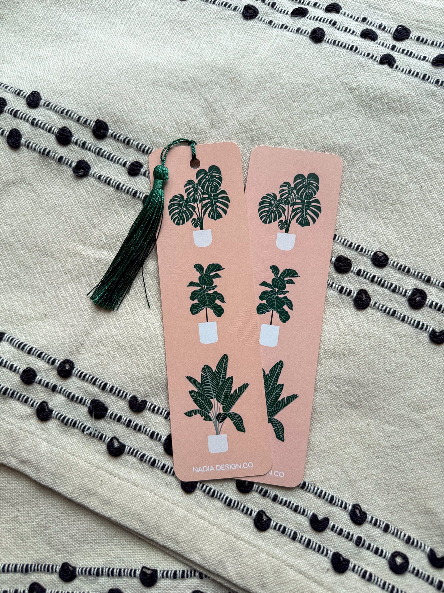 front and back rectangular bookmarks with rounded corners, featuring a green plant illustration and a Colossians 3:23-24 Bible verse, placed on a patterned fabric surface.
