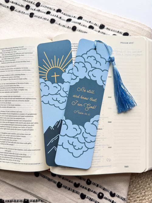Blue mountain cloud illustration Psalm 46:10 bible verse bookmark with tassel on an open book