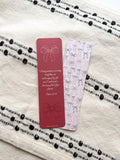 A red bookmark with a bow and the verse Psalm 23:6 printed on it, placedon fabric