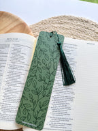 Green leaf-patterned bookmark with tassel on an open book