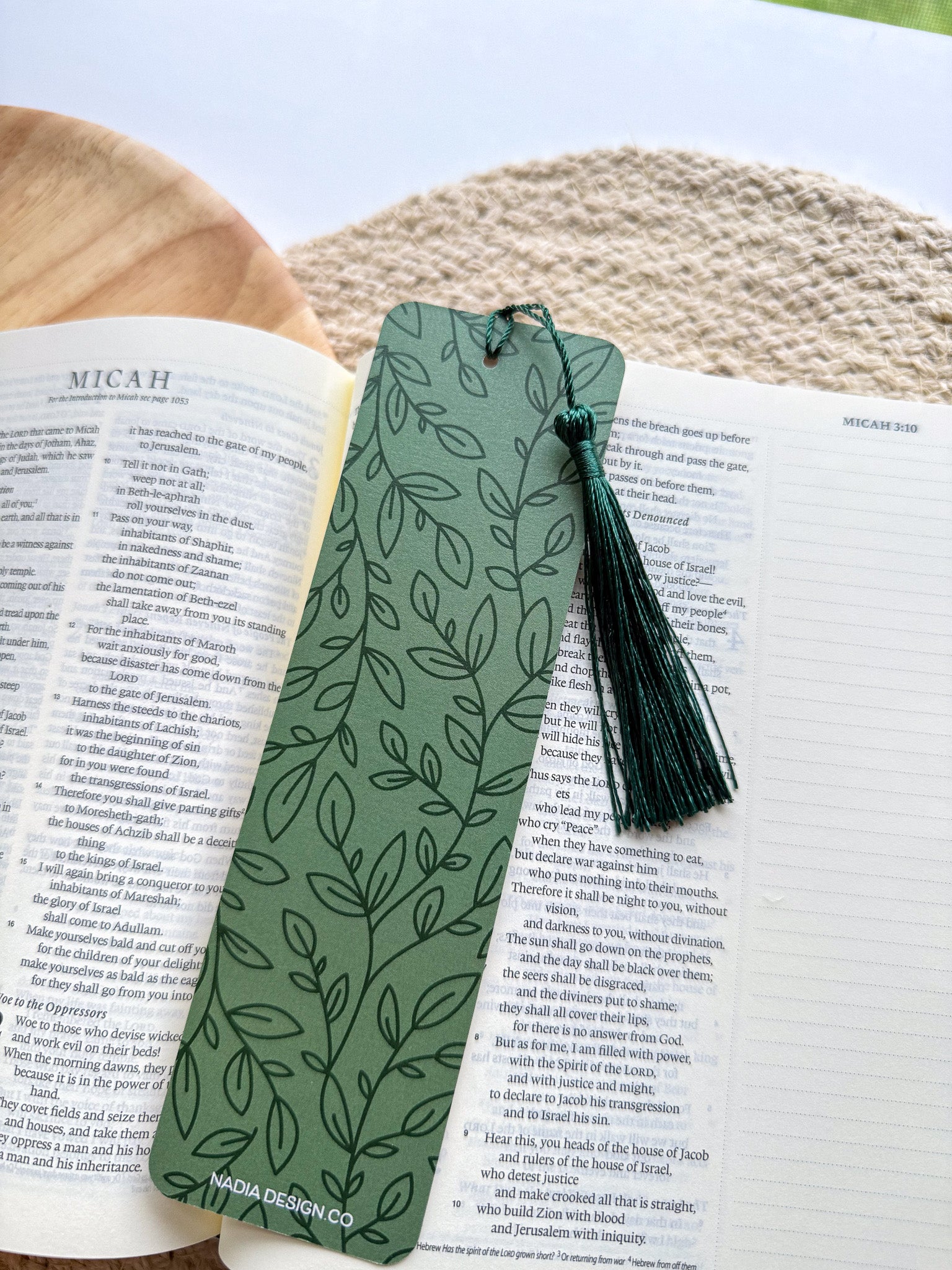 Green leaf-patterned bookmark with tassel on an open book