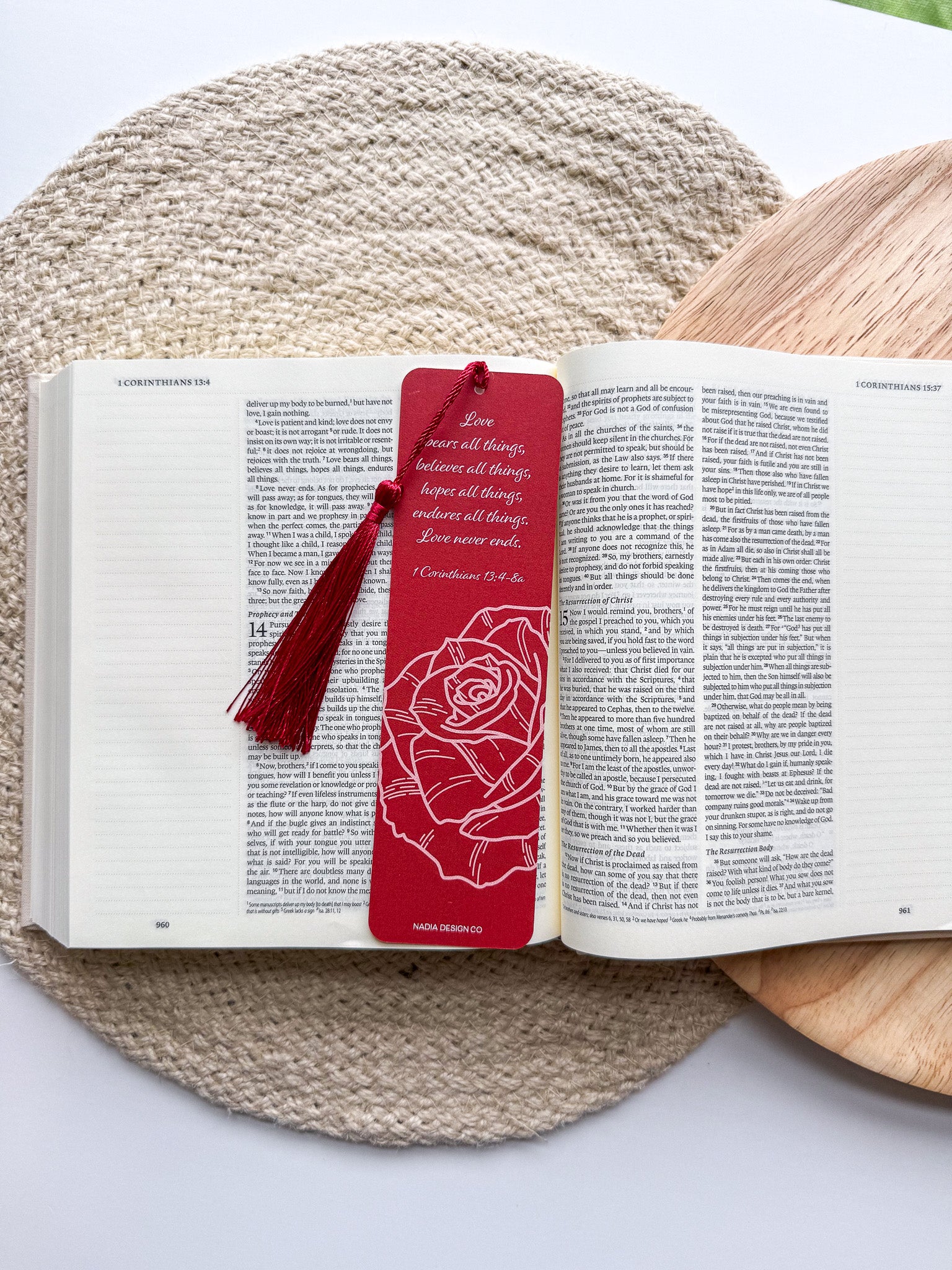 A bookmark with a rose illustration and a red tassel, placed on an open book.