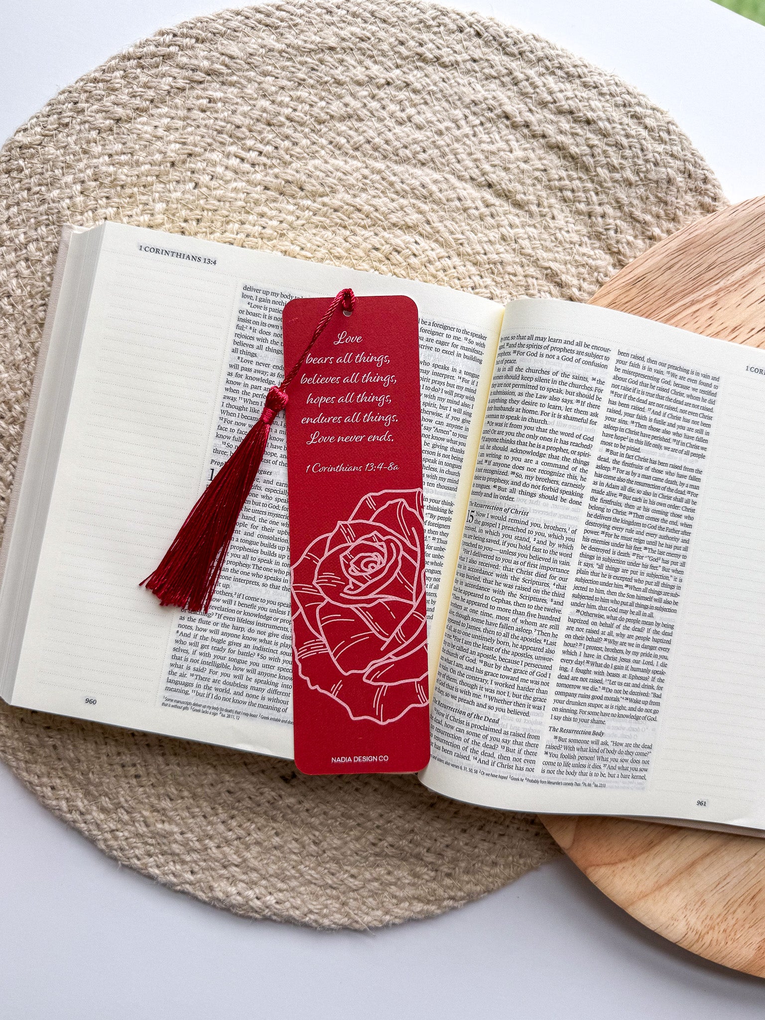 A bookmark with a rose illustration and a red tassel, placed on an open book.