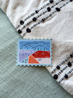 Colorful Colorado-themed stamp shaped ticker on a textured fabric background
