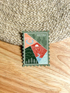 Colorful postage stamp design of Arizona held by a hand against a textured fabric background