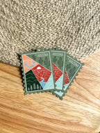 Colorful postage stamp design of Arizona held by a hand against a textured fabric background