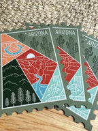 Colorful postage stamp design of Arizona held by a hand against a textured fabric background