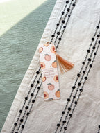 Bookmarks with peach pattern and tassel on a textured surface