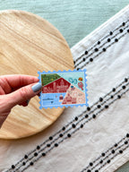 Stylized postage stamp magnet of Connecticut on a textured surface with wooden and fabric elements.