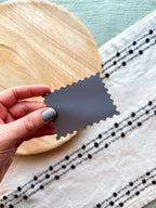Stylized postage stamp magnet of Connecticut on a textured surface with wooden and fabric elements.