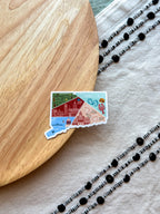 Colorful Connecticut outline design sticker with a scenic design on a textured surface on a wooden object and fabric.