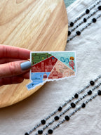 Colorful Connecticut outline design sticker with a scenic design on a textured surface on a wooden object and fabric.