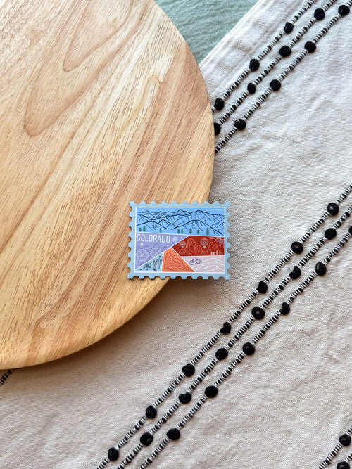 Colorful Colorado-themed stamp magnet on a wooden surface 
