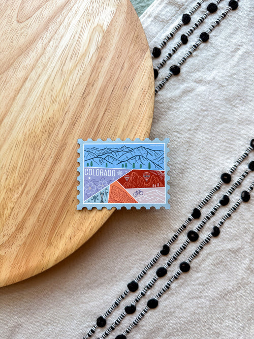 Colorful Colorado-themed stamp shaped magnet on a wooden surface 