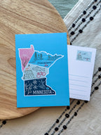Colorful Minnesota-themed postcard on a textured surface