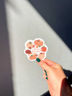 A vinyl sticker with a quote 'I am an Autumn' surrounded by illustrations of pumpkins and autumn leaves held up by a hand