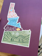 Colorful Idaho themed postcard on a textured surface