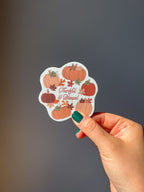 A vinyl sticker with a design of pumpkins, leaves, and the text 'THANKFUL & BLESSED' hand hold it up