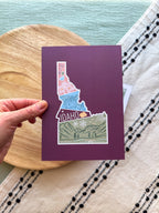 Colorful Idaho themed postcard on a textured surface