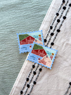 Two decorative postage stamp-shaped stickers on a textured surface with a blurred background.