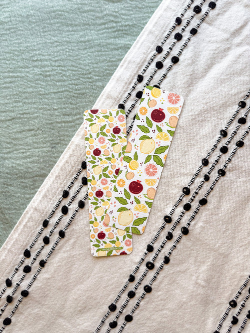 citrus fruit patterned bookmark on a textured fabric surface with a blurred natural background