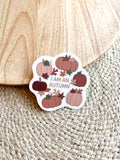 A vinyl sticker with a quote 'I am an Autumn' surrounded by illustrations of pumpkins and autumn leaves on a wooden surface.