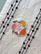Floral sticker with motivational text on a textured fabric background