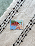 Connecticut Postcard featuring a colorful illustration of a map and buildings, nature themed on a blue background, set against a textured fabric surface.