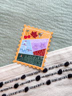 sticker with Wisconsin-themed illustrations, stamp design held by a hand on a textured fabric background