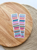 colorful pile of books illustrated bookmarks with quotes on the spin on a wooden background