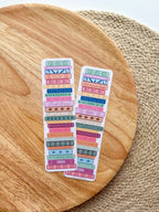 colorful pile of books illustrated bookmarks with quotes on the spin on a wooden background