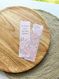 Open book with a pink bookmark featuring floral designs and text "in Christ alone my hope is found" on a woven surface.