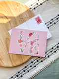 Floral 'LOVE' card on a wooden surface and showing back of card