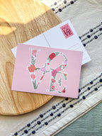Pink card with floral 'LOVE' design on a wooden surface