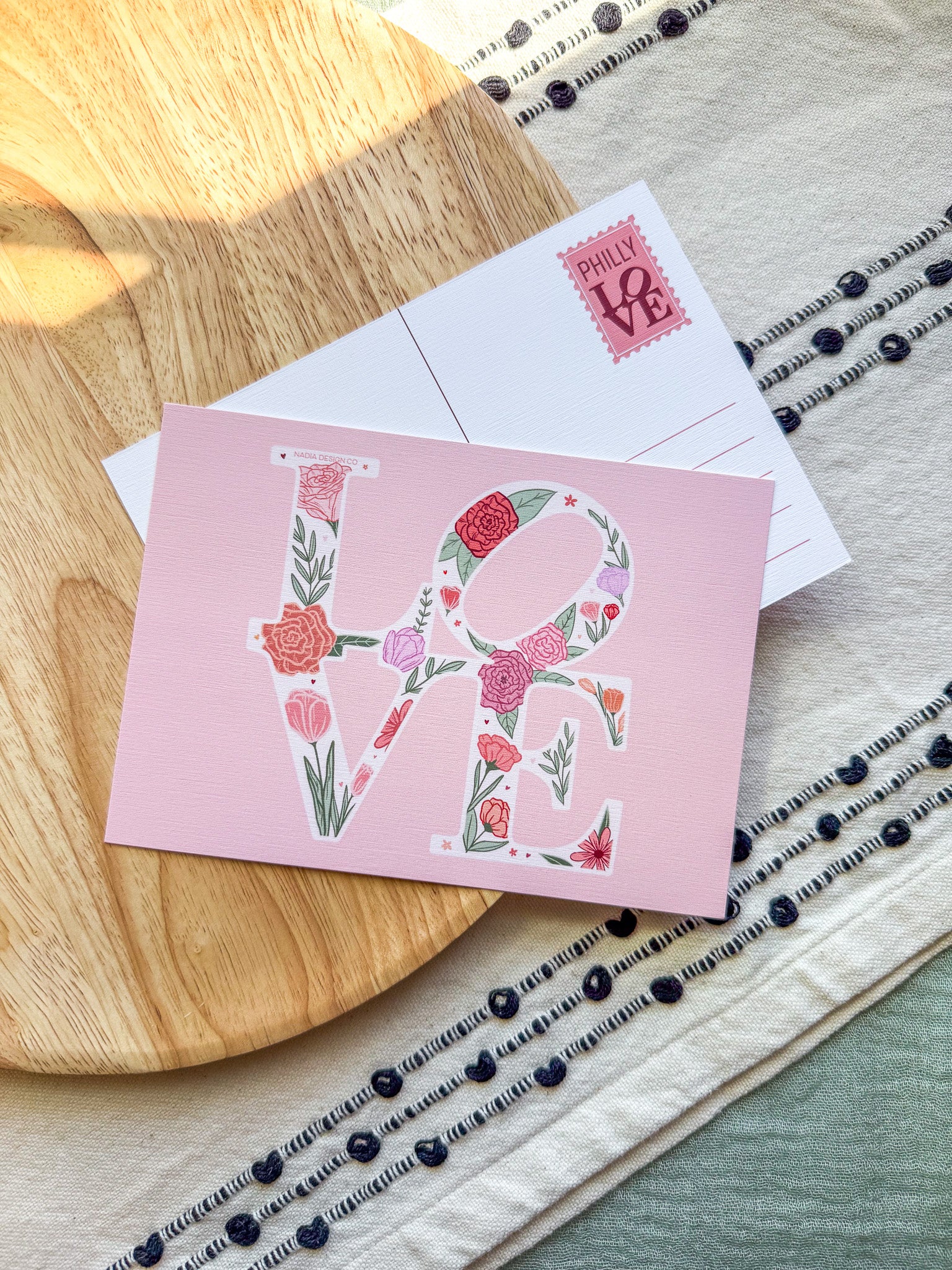 Pink card with floral 'LOVE' design on a wooden surface