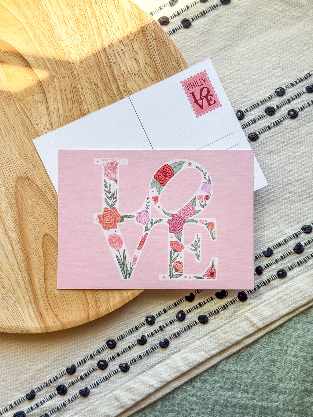 Floral 'LOVE' card on a wooden surface with a patterned background