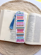 colorful pile of books illustrated bookmarks with quotes on the spine atassel on a wooden background