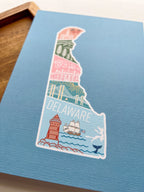 A postcard with an illustration of Delaware state in a colorful artistic style on a blue background.